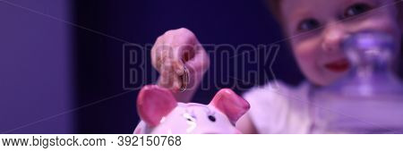 Portrait Of Lovely Child Putting Coin In Pink Piggy Bank. Smiling Charming Girl Saving Up Money For 