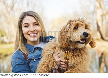 Happy Labradoodle Dog And Woman Outside At The Park