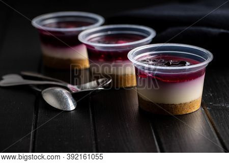 Sweet desssert. Cheesecake cup on black wooden table.