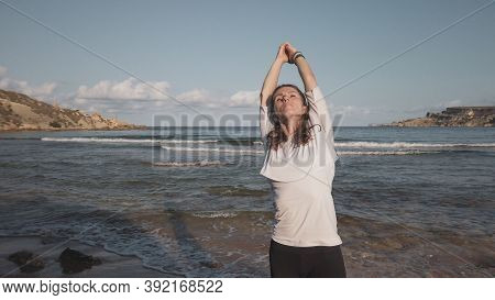 Young Caucasian Brunette Woman Doing Youga On The Sandy Beach In The Morning. High Quality Photo