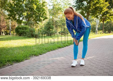 Full Length Shot Of A Sportswoman Massaging Her Injured Knee At The Park. Female Jogger Suffering Fr