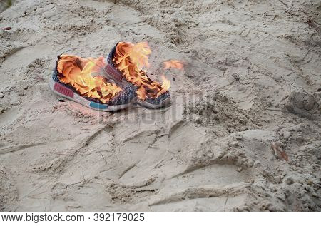 Burning Sports Sneakers Or Gym Shoes On Fire Stand On Sandy Beach Coast. Athlete Burned Out. Physica