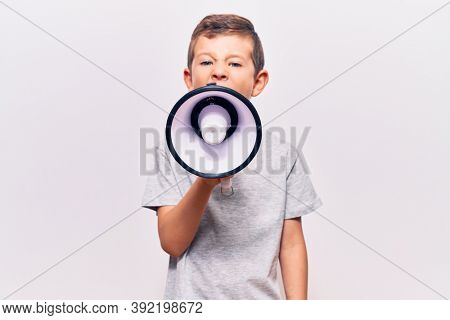 Adorable caucasian kid boy with angry expression. Screaming loud using megaphone standing over isolated white background