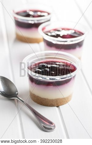 Sweet desssert. Cheesecake cup on white wooden table.