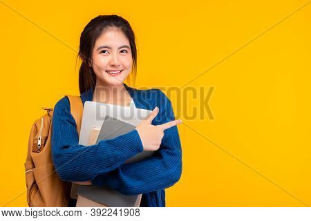 Happy Asian Female College Student Smiling At Camera On Yellow Background, Holding Tablet And Book, 