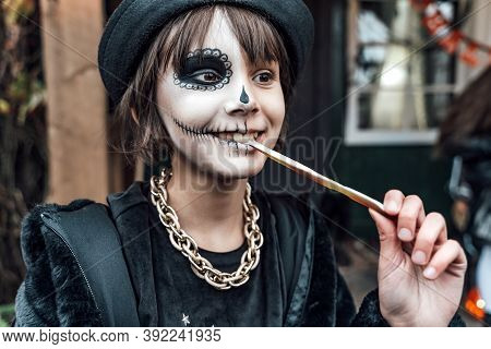 Beautiful Scary Little Girl Celebrating Halloween, Chewing Gummy Worm. Terrifying Face Makeup And Wi