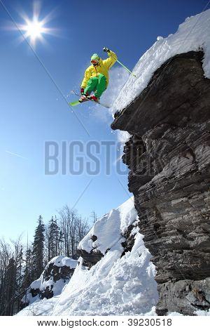 Skier jumping against blue sky from the rock