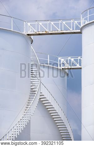 Low Angle View Of Curve Spiral Staircase On White Storage Fuel Tanks In Vertical Frame
