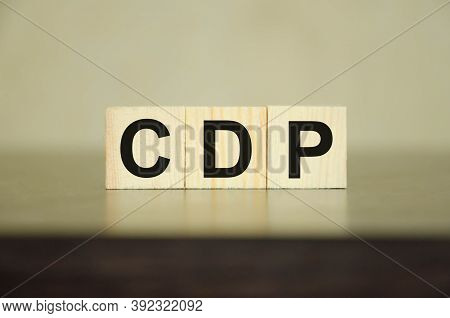 The Word Is Written On Wooden Cubes That Lie On A Black Table. The Word Cdp Is Present. This Stands 