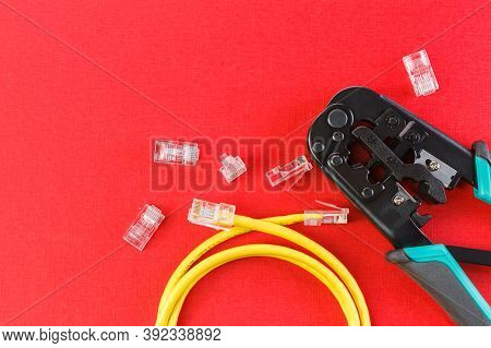 Computer Network Laying Concept. Crimper Tool And Transparent Connectors Connectors On Red Backgroun