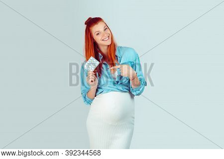 Vitamins And Minerals Suppliments I Take During Pregnancy. Content Woman With Baby In Belly Holding 