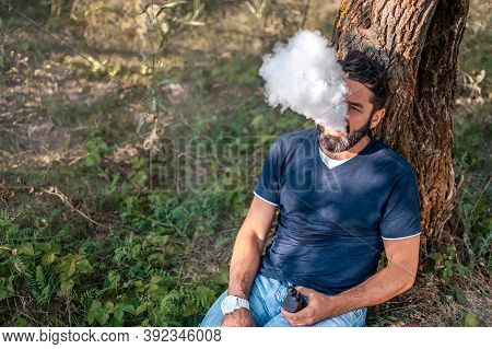 Stylish Vaper Smoking An Electronic Smoke Device Outside. Alternative To Smoking.