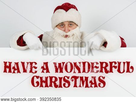 New Year And Christmas Concept. Santa Claus Points His Fingers At The Board With The Text - Have A W