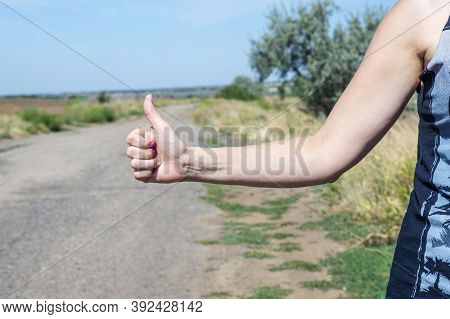 Thumb Up Is The Symbol Or Sign Of Help Or Favor Or Hitchhike From Hitchhiker On A Road. Woman Is Sho