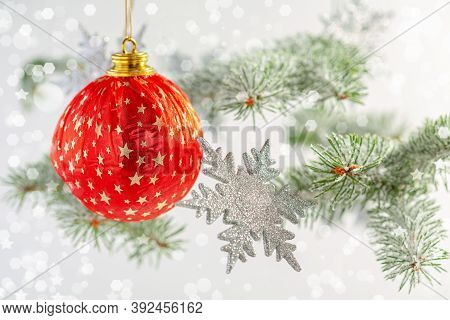 Red Christmas Ball, Silver Snowflakes And Snow-covered Fir Branches Close-up, Selective Focus. Chris
