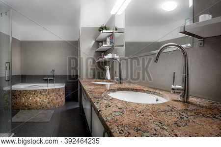 Modern Bathroom In Cool Style With Glass Shower And Bathtub Lined With Red Stones And Marble.