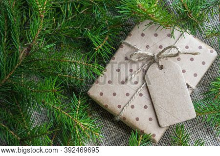 Gift Box With A Tag On The Background Of Fir Branches. Has Space For Text