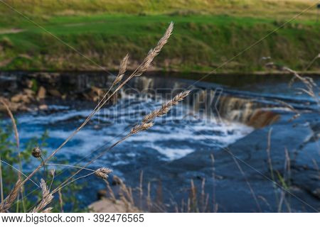 Waterfall, Water Flowing From The River Falls Down. A Stormy River With A Brown Hue.