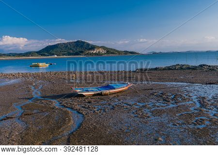 Small Fishing Boat Stranded On Tidal Mud Flats At Low Tide.