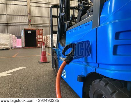 Electrical Forklift Vehicle Park And Plug In For Charging Battery Inside Of Logistic Warehouse. Alte