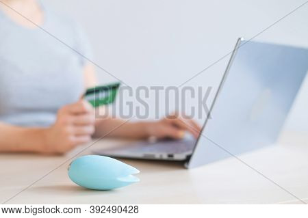 A Faceless Woman Holds A Credit Card And A Clitoral Vibrator While Sitting At A Laptop. Online Sex I