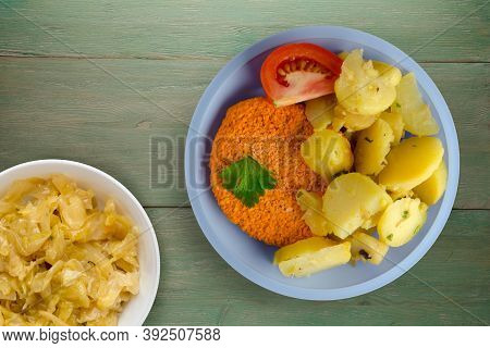 Meatball With Potatoes On Green Wooden Background. Meatball With A Slice Of Tomato On Light Blue Pla