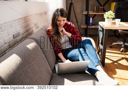 Woman Teleworker Works At Home With A Laptop. She Is In Smart Working Due To Covid-19 Pandemic