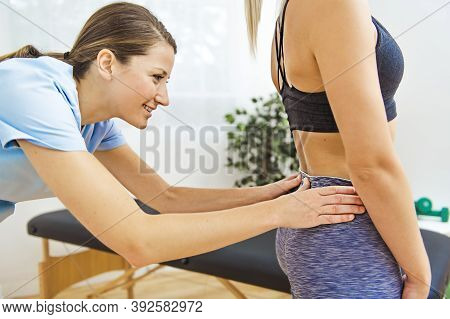 A Modern Rehabilitation Physiotherapist At Work With Client. Working On Lower Back.