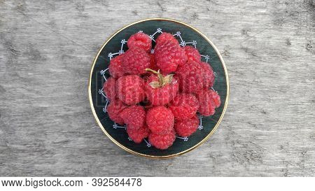 Bright, Juicy, Tasty, Red Raspberries In A Plate On A Wooden Table Top.