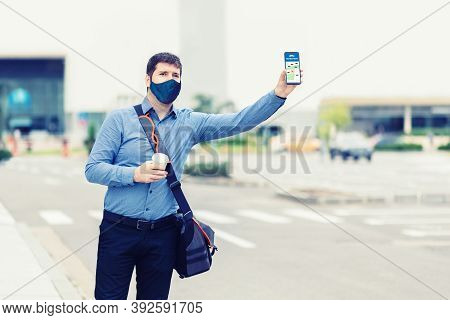 Man Passenger With Protective Face Mask Using Mobile Taxi App Waiting Cab Or Ride Share With Hand Up