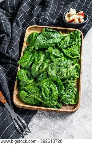 Young Spinach Leaves In A Wooden Bowl With Goat Cheese. Gray Background. Top View