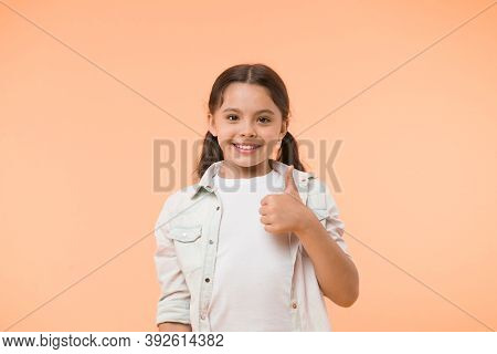Good Quality. Kid Girl Shows Thumb Up Gesture Recommends Yellow Background. Child Highly Recommend W