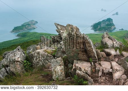 Bay Of The Sea And Large Rocks From The Hilltop Of The Mountainous Coast With An Island In The Backg