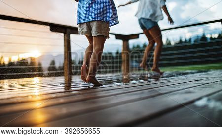Unrecognizable Mother With Small Daughter Playing On Patio Of Wooden Cabin, Holiday In Nature Concep