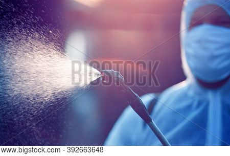 Man in protective equipment decontaminating and spraying on a public place as a prevention against Coronavirus disease 2019, COVID-19. Coronavirus pandemic.