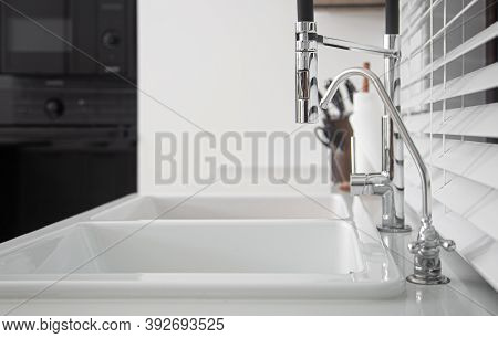 Modern Designer Chrome Water Tap Over Stainless Steel Kitchen Sink Close Up.