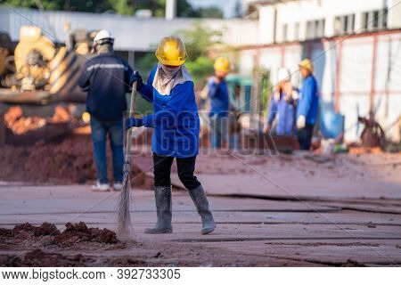 Construction Worker Sweepers Soil Debris With Brush Broom In The Construction Site