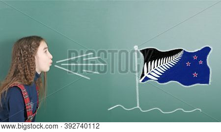 Pre-adolescent Girl Blowing On The School Board Drawn On The Blackboard New Zealand Flag. High Resol