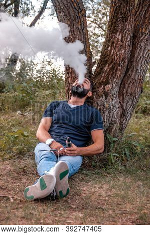 Stylish Vaper In The Fresh Air Smoking An Electronic Cigarette. Vaping Activity.