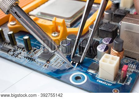 A Mosfet Transistor Key Is Soldered Out Of Computer Board Using A Soldering Iron And Tweezers