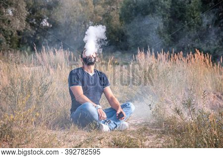 Modern Vaper Enjoying An Vape On The Forest Floor. The Man Smokes.