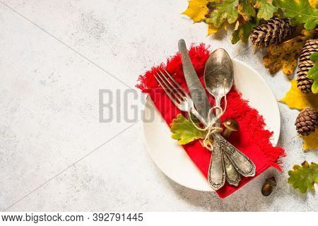 Thanksgiving Food Concept. Autumn Table Setting With White Plate, Silverware And Fall Decorations At