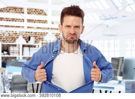 Aggressive man tearing shirt apart on his chest, looking wild.