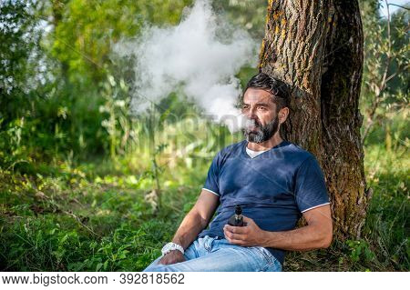Confident Smoker Blowing A Lot Of Smoke Using Vape Electronic Smoke Device. Modern Ways Of Quitting 