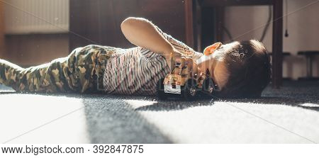 Lovely Small Boy Playing On The Floor With A Toy Car In A Sunny Day