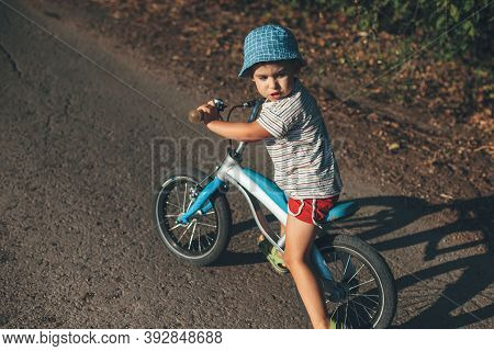 Upper View Photo Of A Caucasian Boy Looking Back While Riding A Bike On A Country Road
