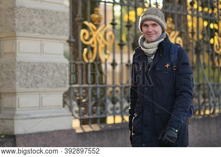 Fashionable man walking along  ?ast iron fence in historical center of Saint Petersburg, Russia