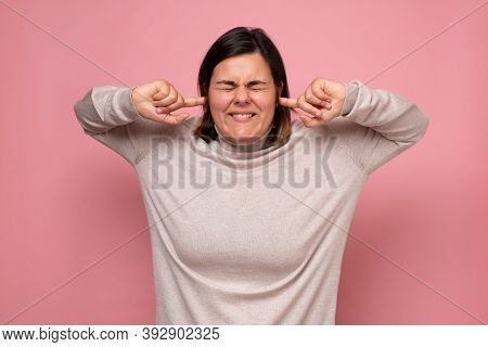 Annoyed Young Woman Plugging Her Ears To Avoid Loud Noise, Having Irritated Look