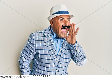 Mature middle east man with mustache wearing vintage and elegant fashion style shouting and screaming loud to side with hand on mouth. communication concept. 