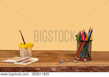 Watercolor Set, Paintbrush, Binder Clips, Felt-tip Pens And Colorful Pencils In Stand On Wooden Desk